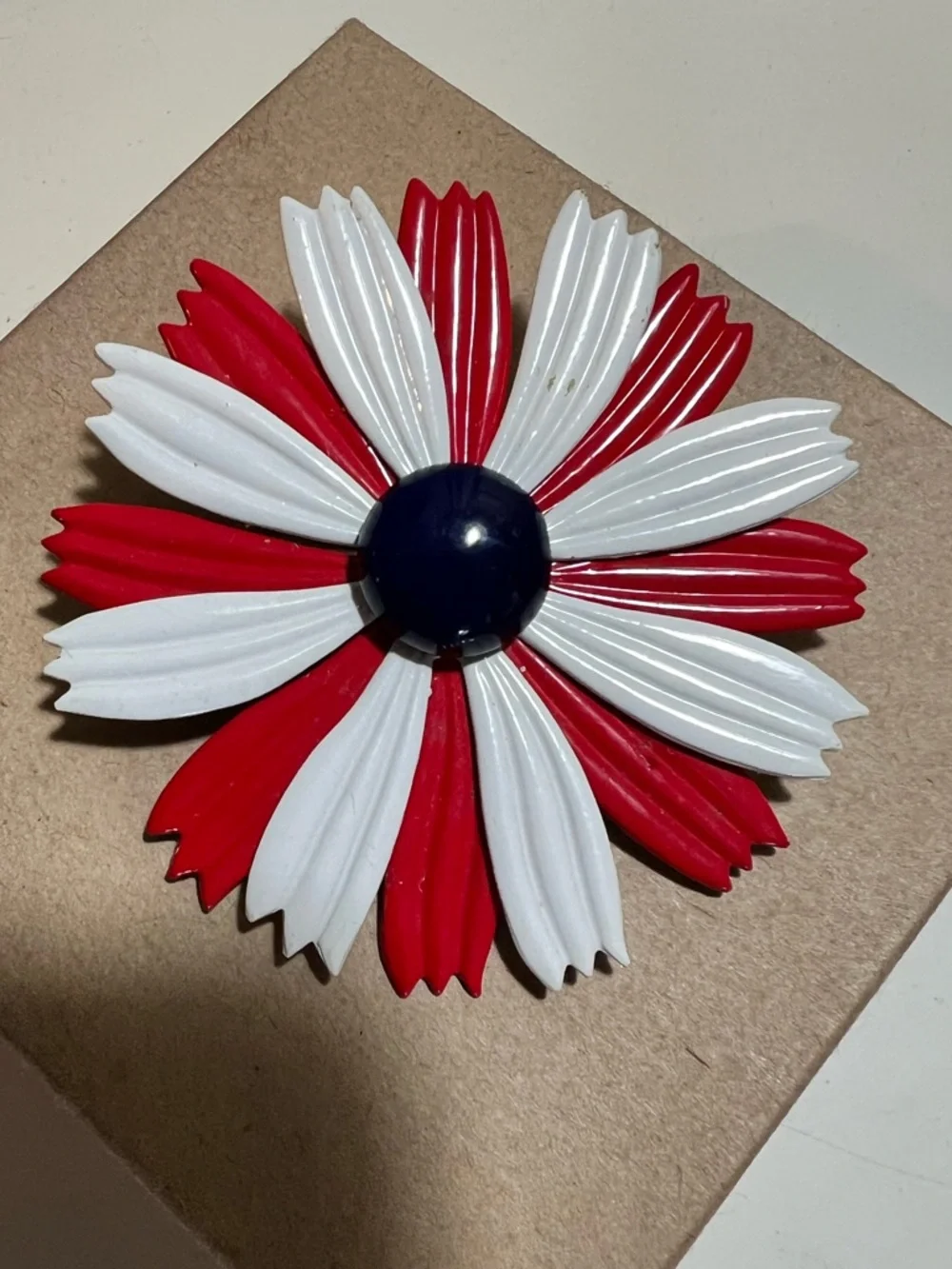 1960s enamel brooch with red and white petals and blue dome center.